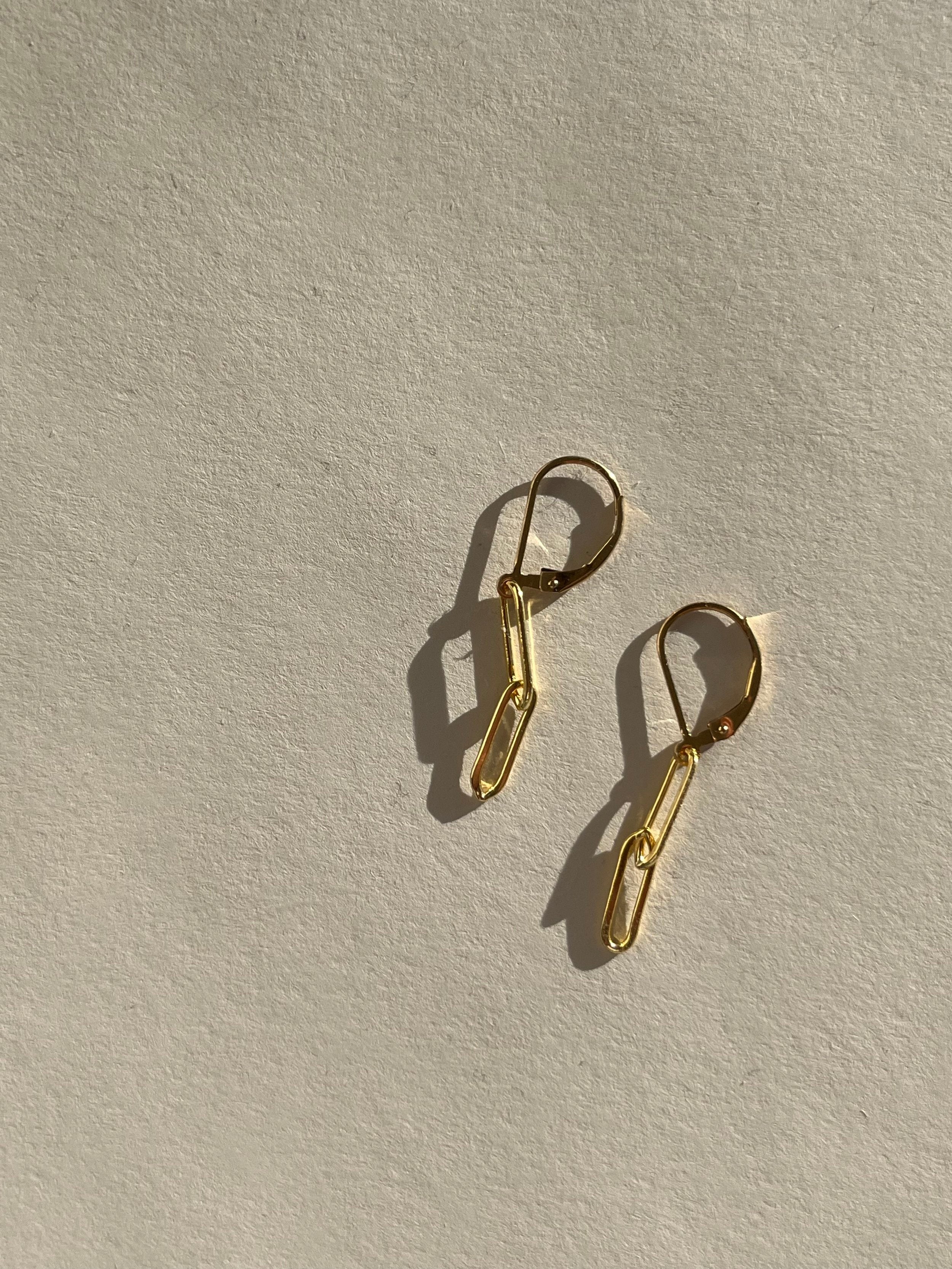 Pair of Large Paperclip Double Stacked Leverback Earrings in yellow gold-filled displayed flat on a neutral beige backdrop