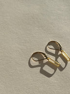 Pair of large paperclip leverback earrings in yellow gold-filled resting on a neutral background, showcasing their sleek, minimalist design