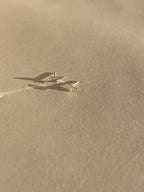 Pair of sterling silver lightning bolt stud earrings shown on a light backdrop
