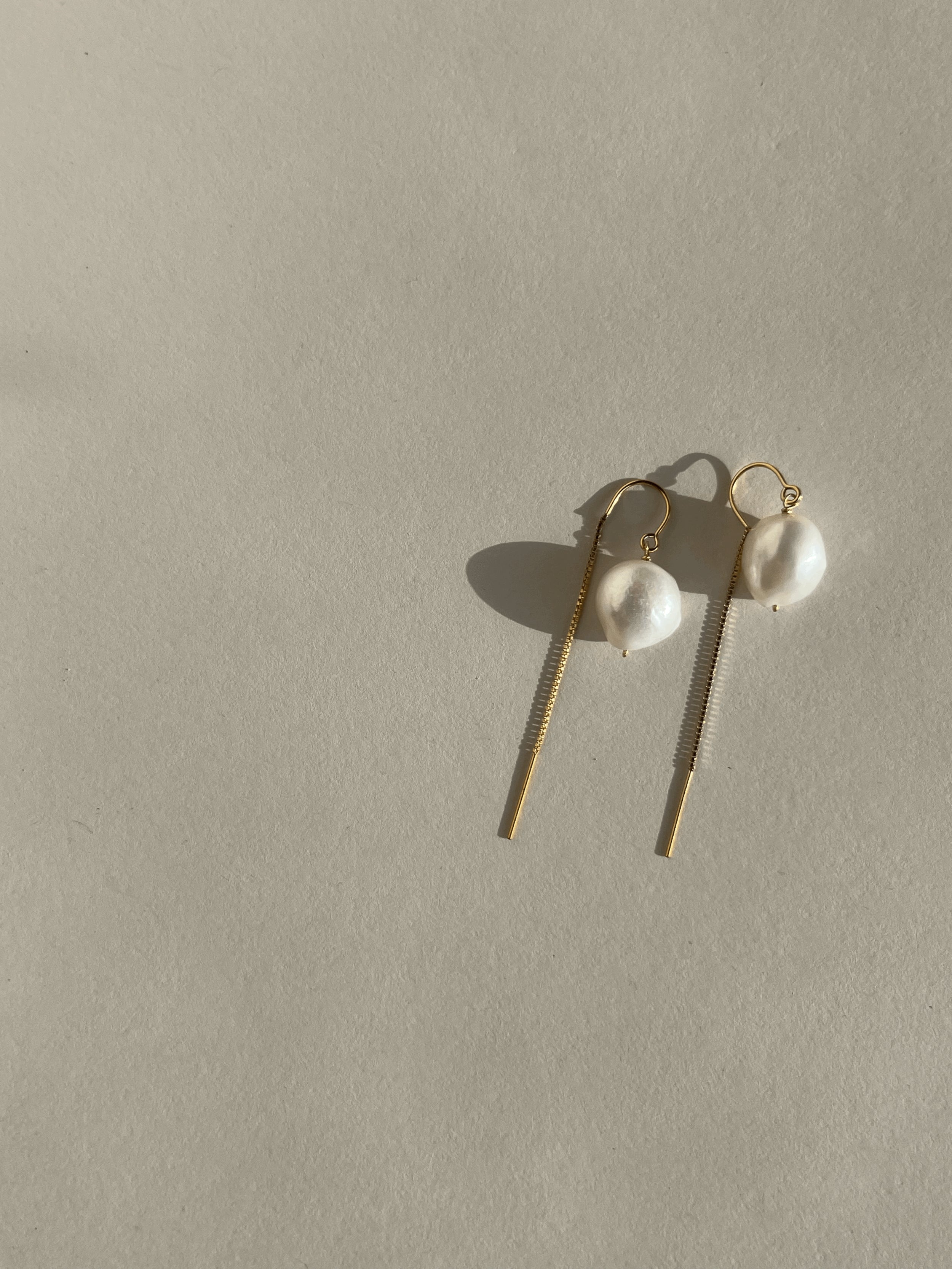 Medium Freshwater Pearl Drop Threader Earrings displayed on a cream backdrop, showing the elegant U-threader design and lustrous pearl drops