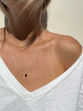 Model wearing minimalist yellow gold-filled garnet drop necklace with natural stone pendant, styled with a white v-neck top