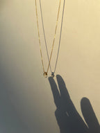 Citrine drop necklace hanging with shadow of hand creating the illusion of a hand touching the necklace drop