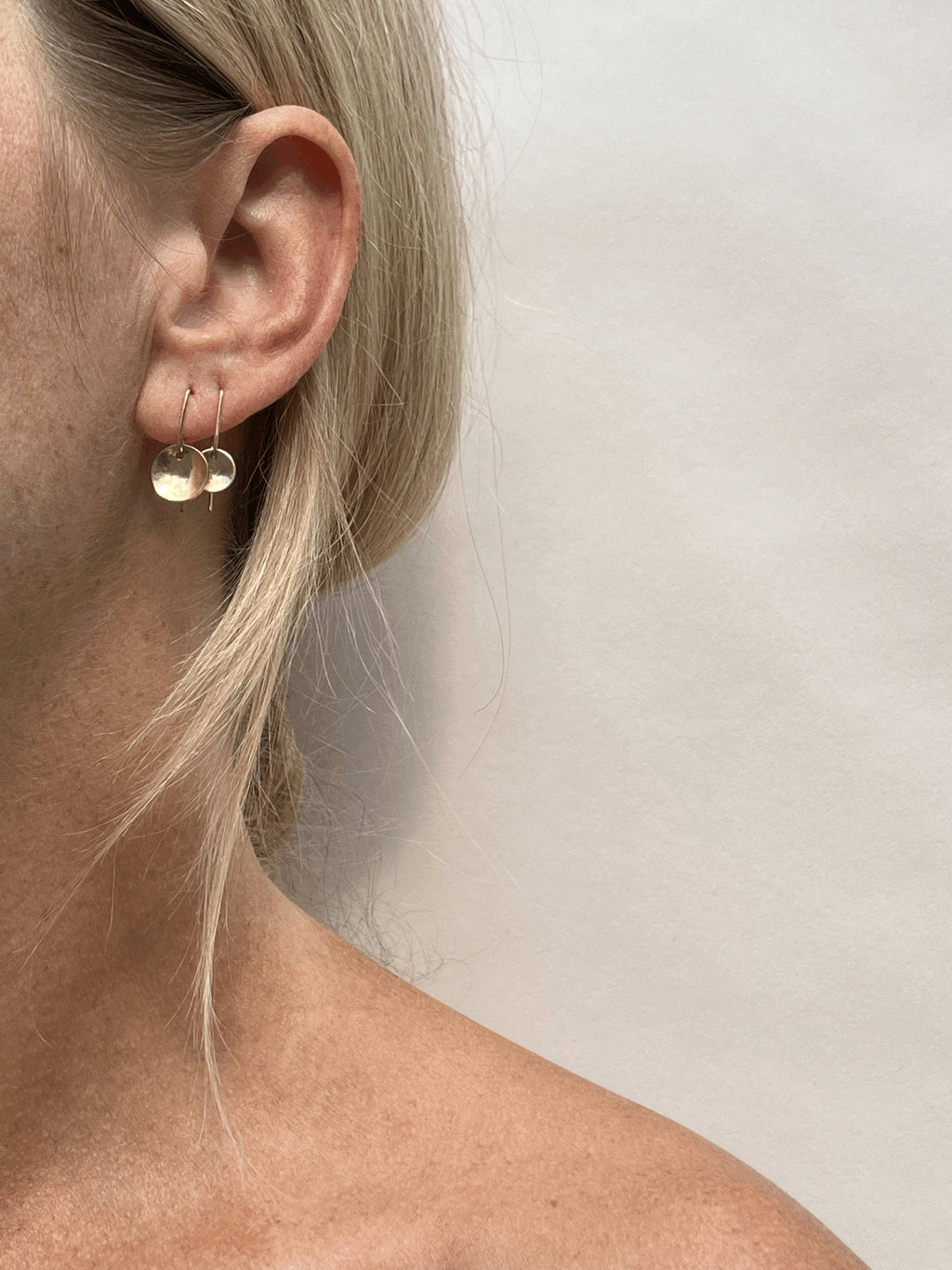 Model wearing yellow gold-filled Minimalist Disc Dangles with 9mm discs in her first piercing and 7mm discs in her second, showing natural ear profile
