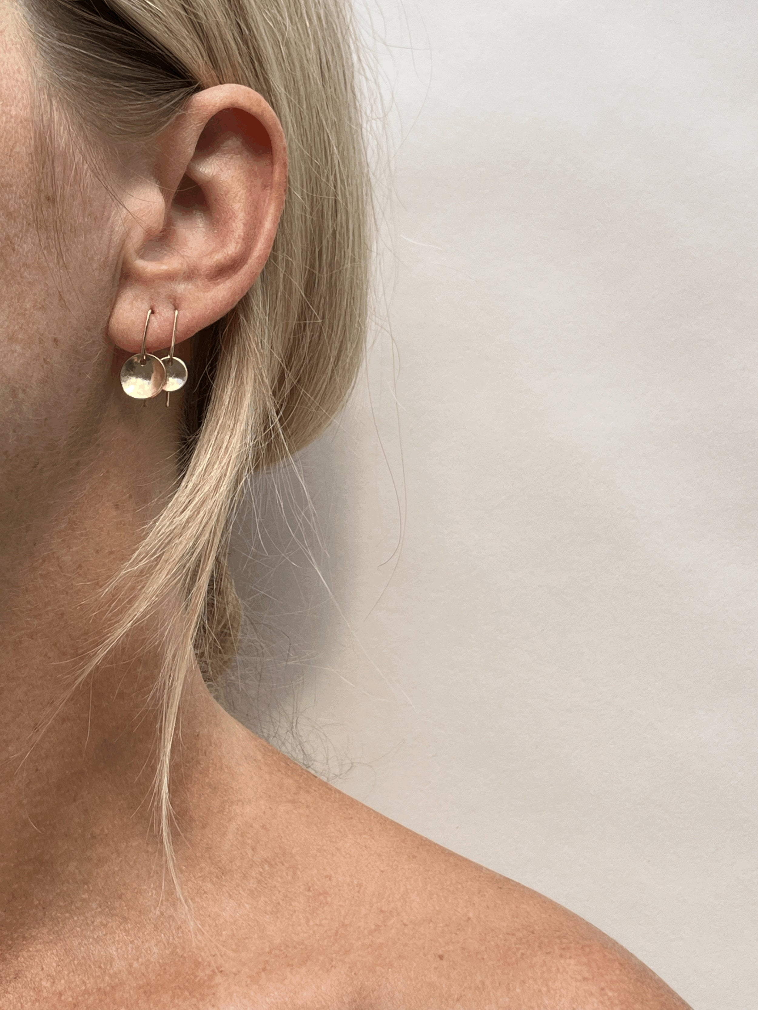 Model wearing yellow gold-filled Minimalist Disc Dangles with 9mm discs in her first piercing and 7mm discs in her second, showing natural ear profile