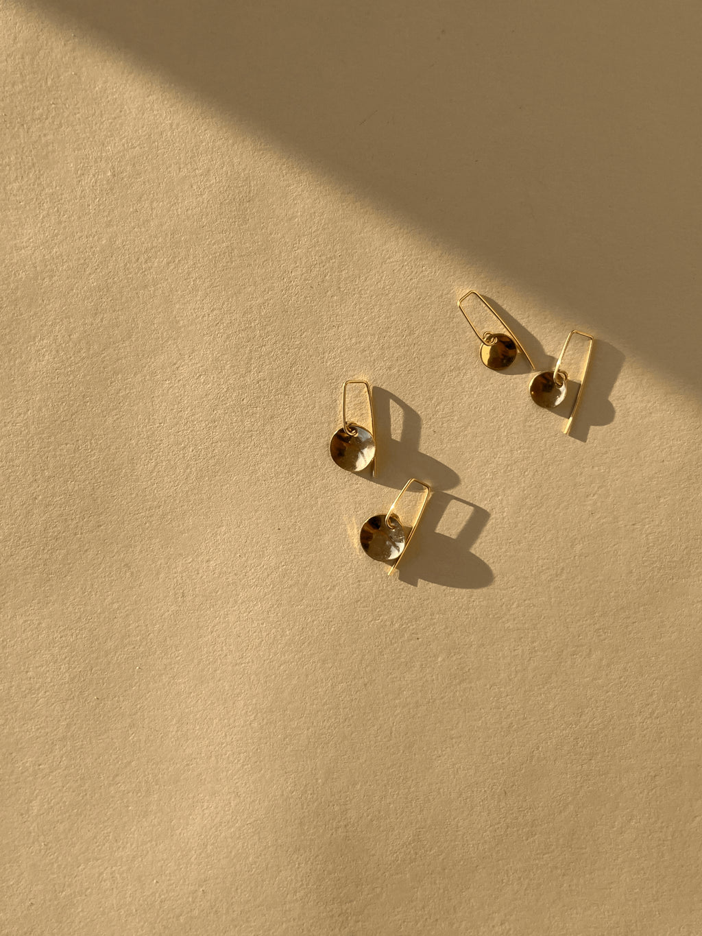 Overhead product shot of yellow gold-filled Minimalist Disc Dangles arranged side by side, showcasing the two disc sizes and elegant wire hooks
