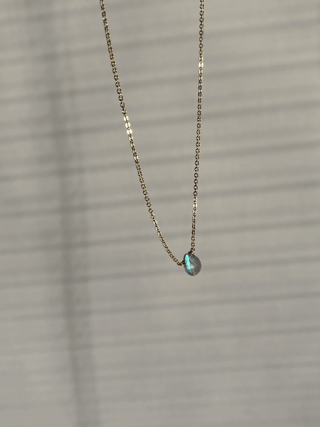 Close-up of yellow gold-filled dainty labradorite drop necklace on minimalist chain by Thalken
