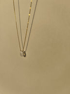 Yellow gold-filled minimalist moonstone necklace suspended in warm light with soft shadows, showing the natural moonstone drop