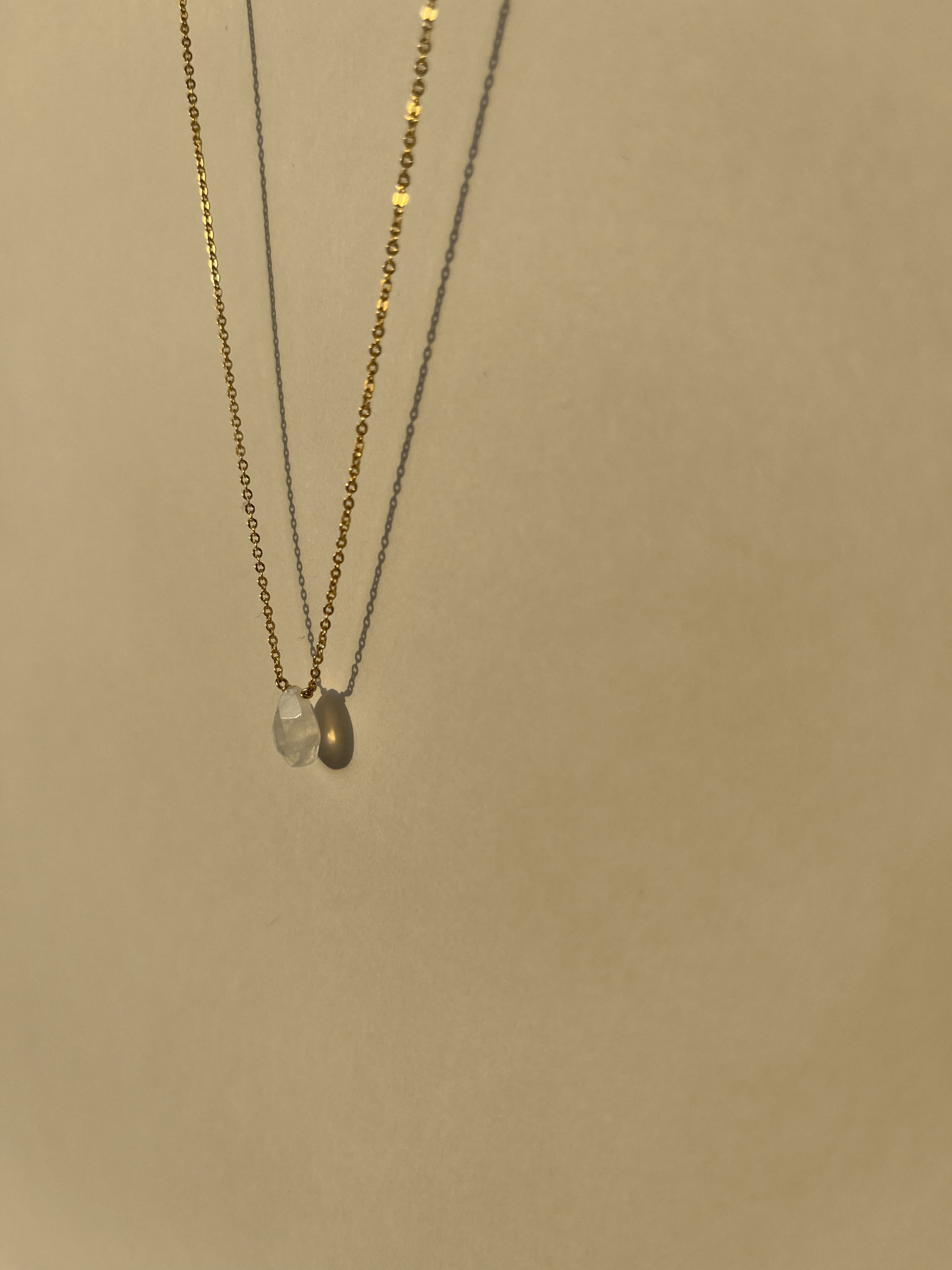 Yellow gold-filled minimalist moonstone necklace suspended in warm light with soft shadows, showing the natural moonstone drop