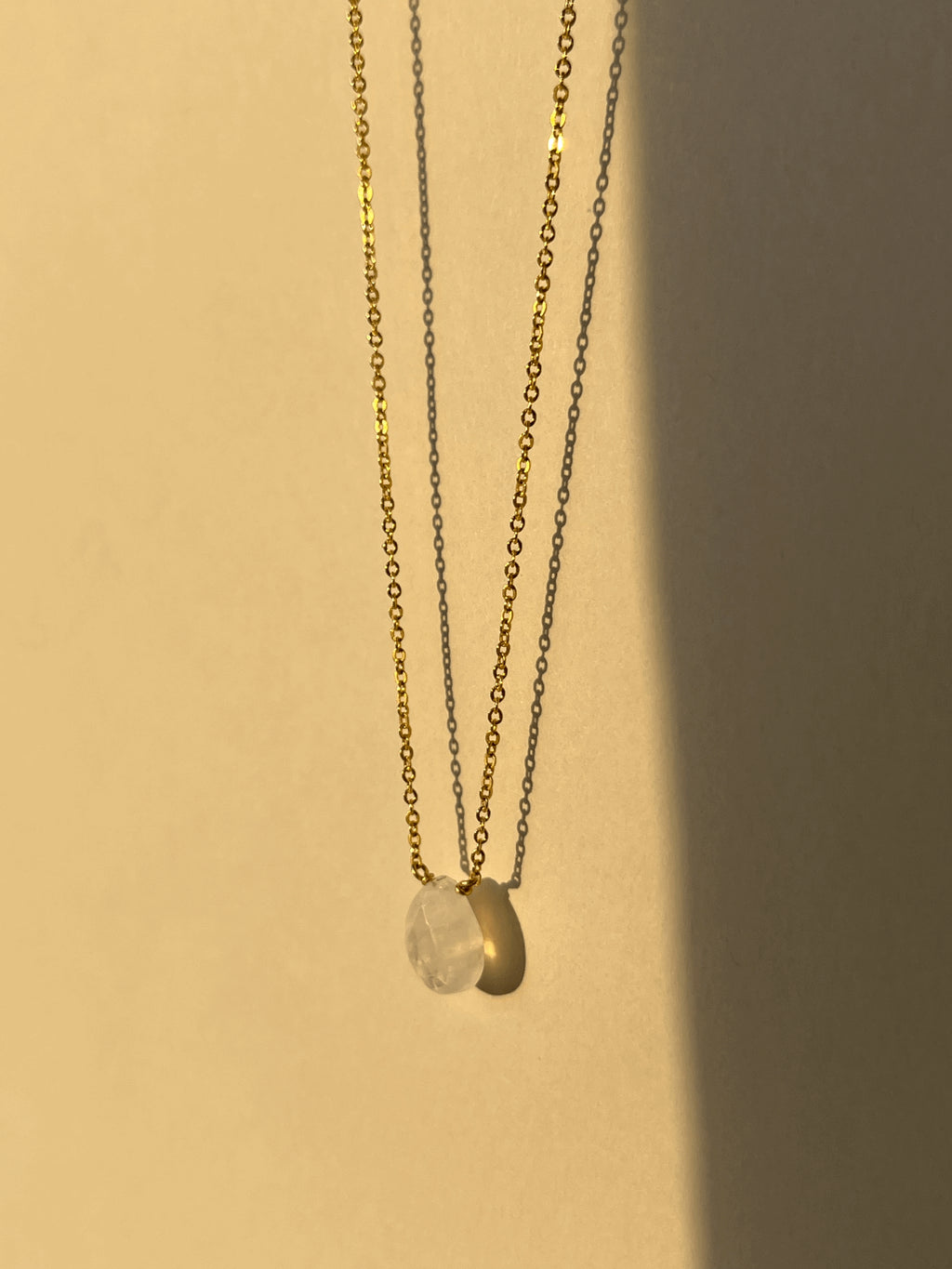 Close-up of yellow gold-filled moonstone drop necklace suspended in warm light, showcasing the semi-translucent natural gemstone and delicate chain