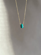 Minimalist turquoise drop necklace in yellow gold-filled, suspended in soft light with natural shadows highlighting the chunky gemstone