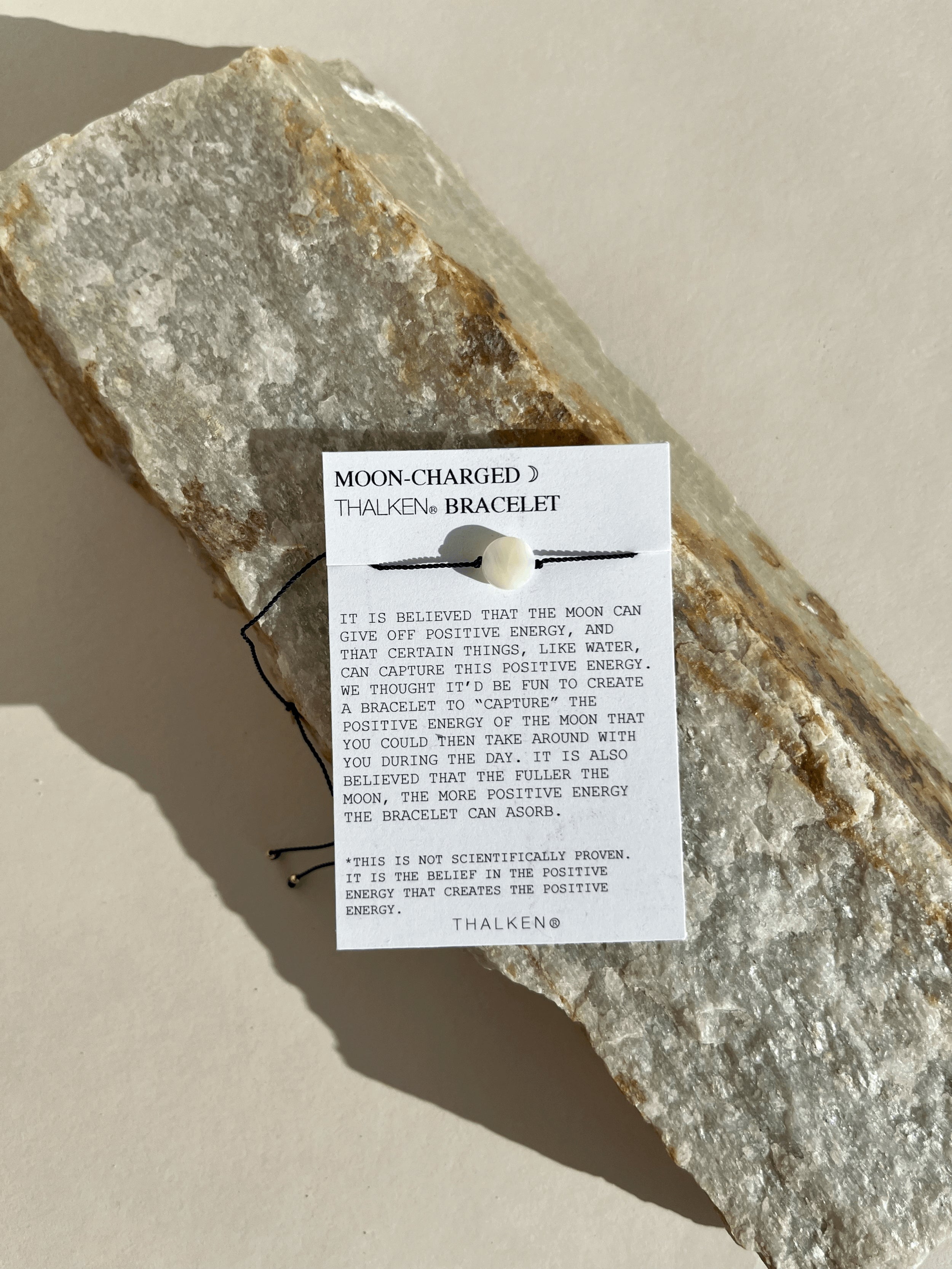 Close-up of the Moon Charged bracelet on its mantra card, highlighting the mother-of-pearl bead and cord details