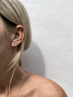 Model wearing a sterling silver moon stud earring in her first ear piercing and a star stud earring in her second ear piercing