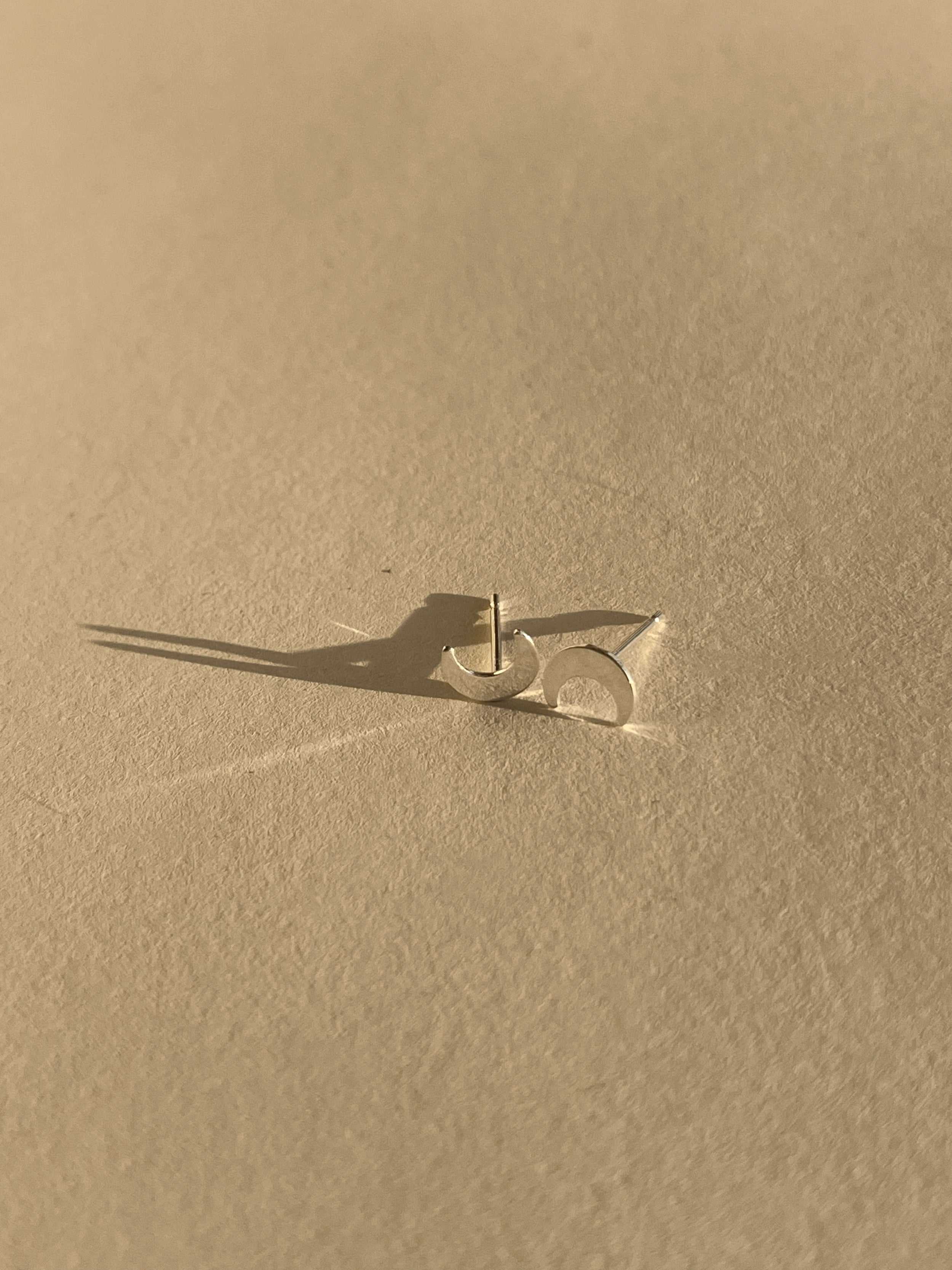 Pair of sterling silver moon stud earrings shown on a light backdrop