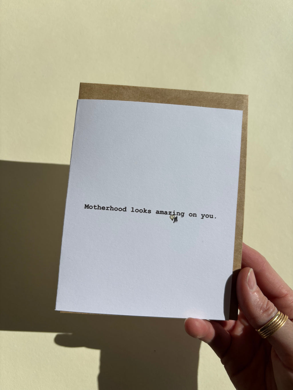 Greeting card held in a hand thats says "Motherhood looks amazing on you."