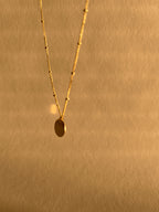 Artistic, slightly blurry shot of the yellow gold-filled My Favorite Necklace swinging in air, emphasizing movement and dainty design