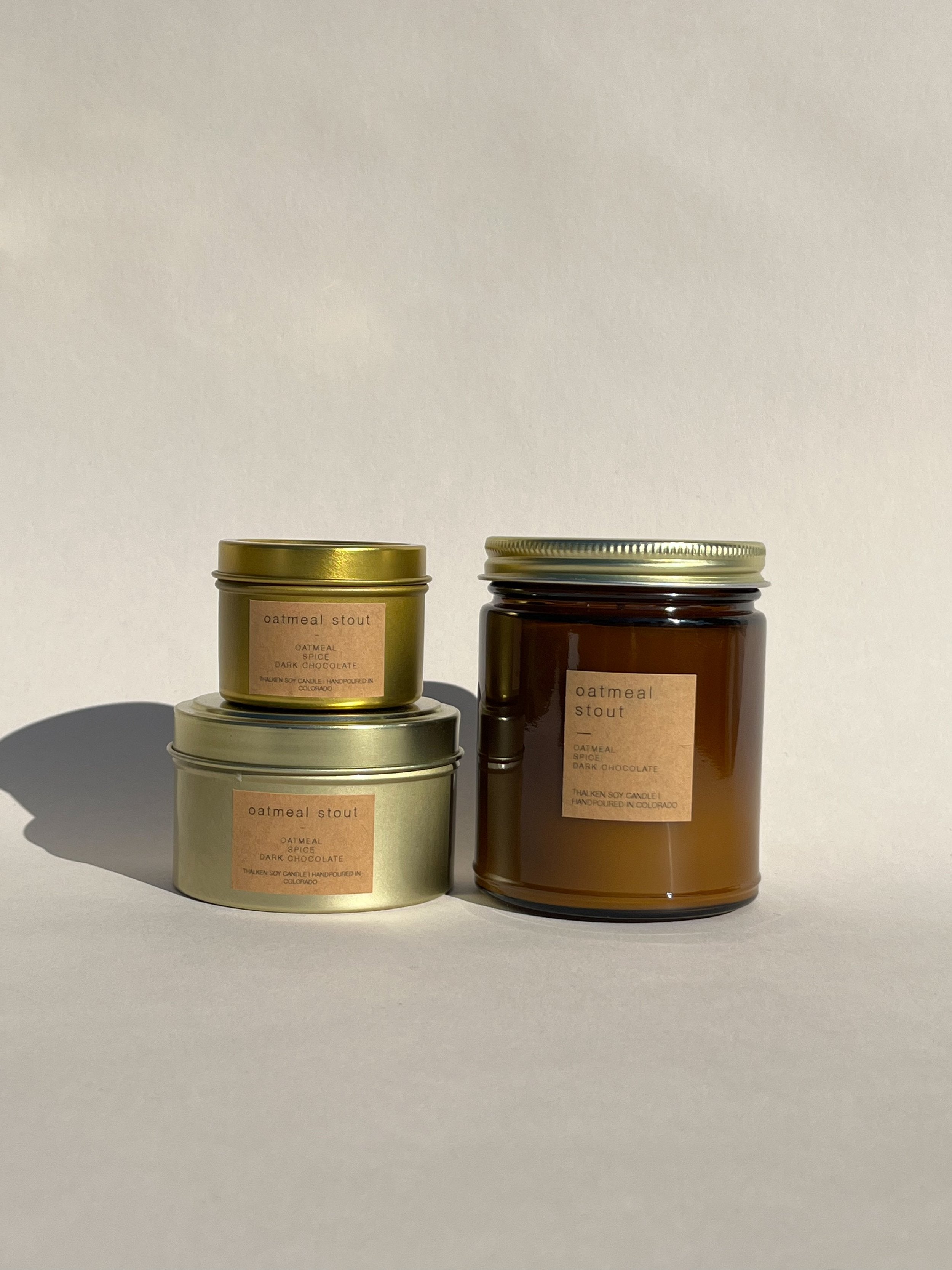 Thalken Oatmeal Stout candle in three containers: small gold tin, medium gold tin, and large brown glass jar