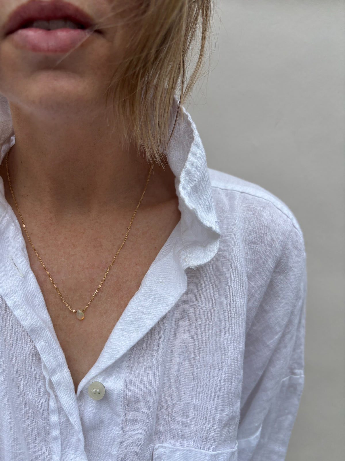 Woman wearing Thalken dainty minimalist Ethiopian opal necklace in yellow gold-filled.