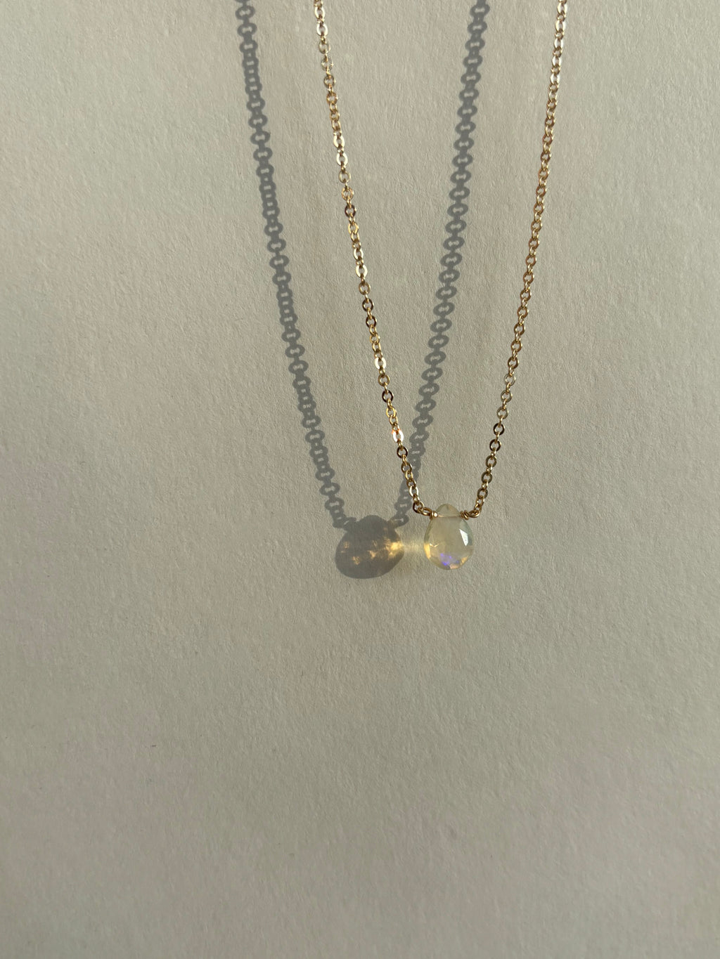 Close-up of Thalken’s dainty yellow gold-filled chain featuring a central real Ethiopian opal drop, different angle