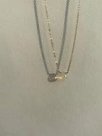 Close-up of Thalken’s dainty yellow gold-filled chain featuring a central real Ethiopian opal drop, different angle