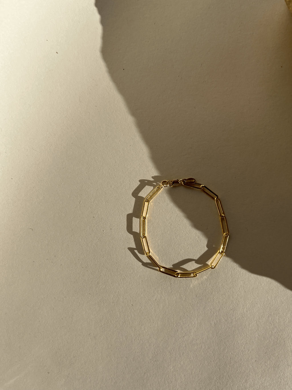 Thalken Large Link Paperclip Bracelet in yellow gold-filled displayed further away on a neutral paper backdrop in warm light