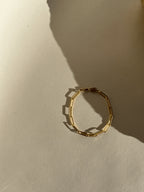 Thalken Large Link Paperclip Bracelet in yellow gold-filled displayed further away on a neutral paper backdrop in warm light