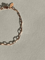 Thalken Small Link Paperclip Bracelet in rose gold-filled displayed on a neutral paper backdrop, positioned to the left