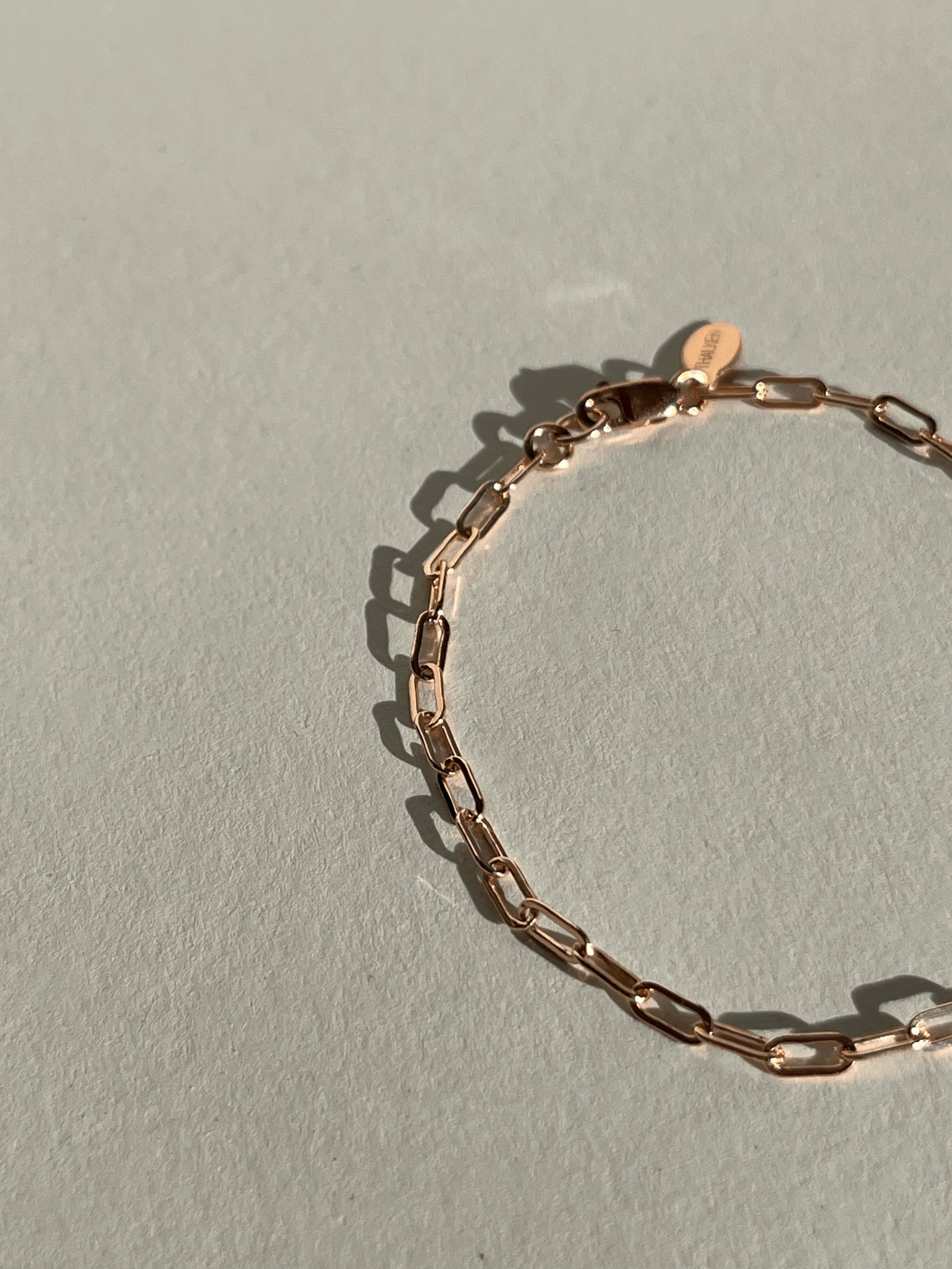 Thalken Small Link Paperclip Bracelet in rose gold-filled displayed on a neutral paper backdrop, positioned to the right