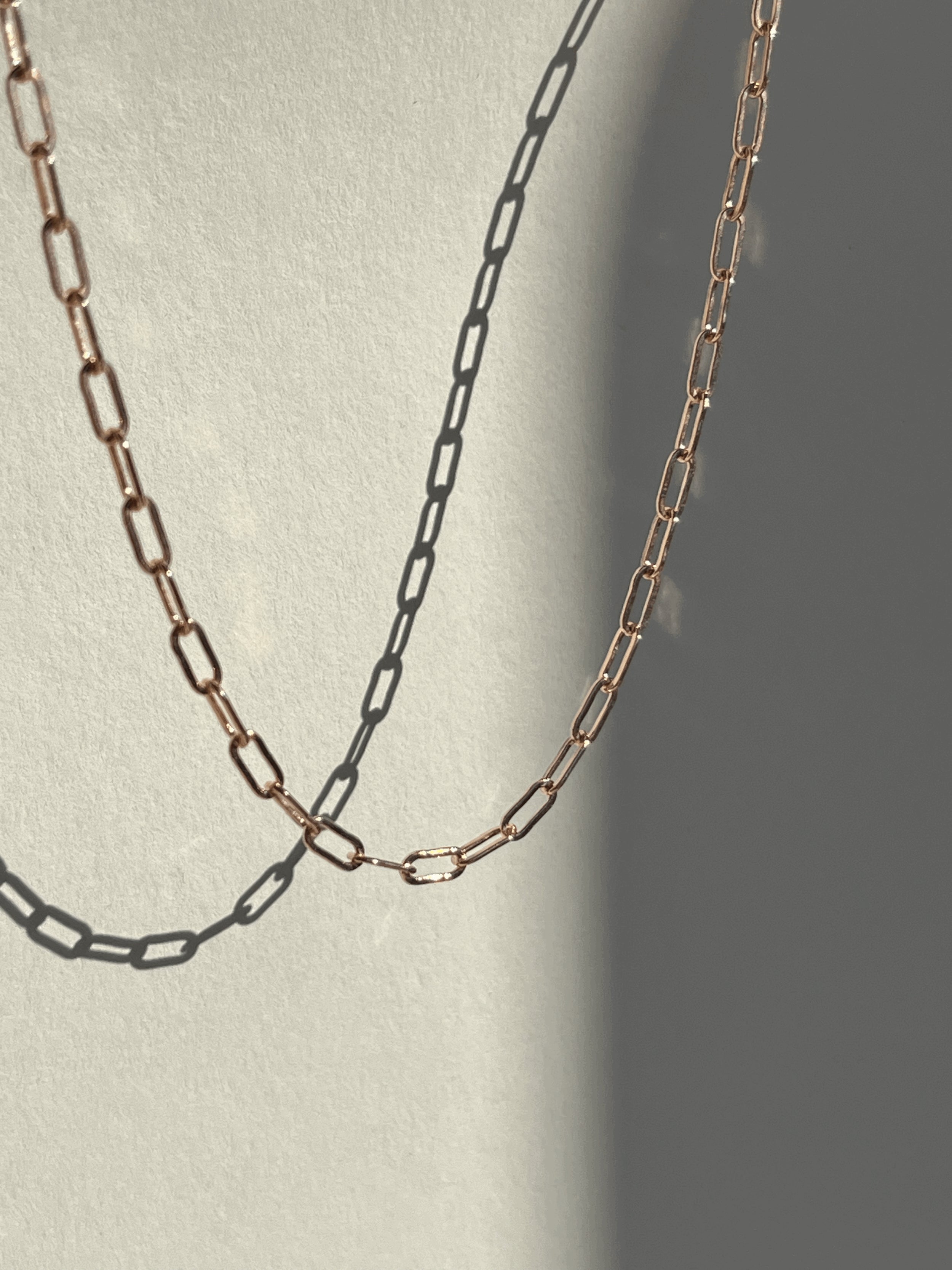 Rose gold-filled small link paperclip necklace suspended in the air, showcasing its delicate elongated links