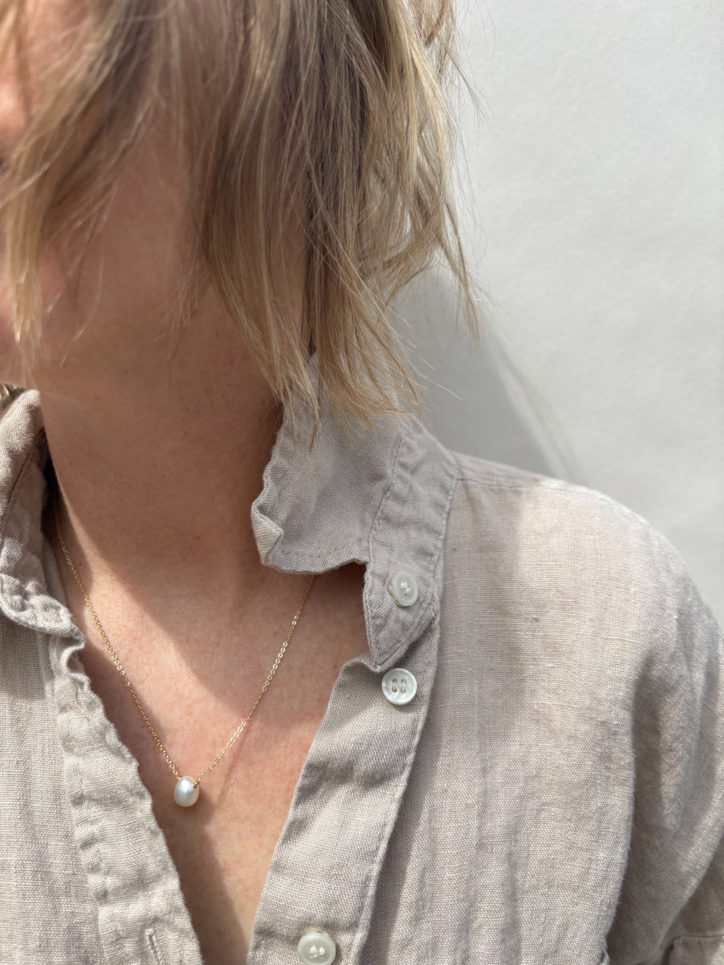 fixed pearl necklce on woman in tan collared shirt