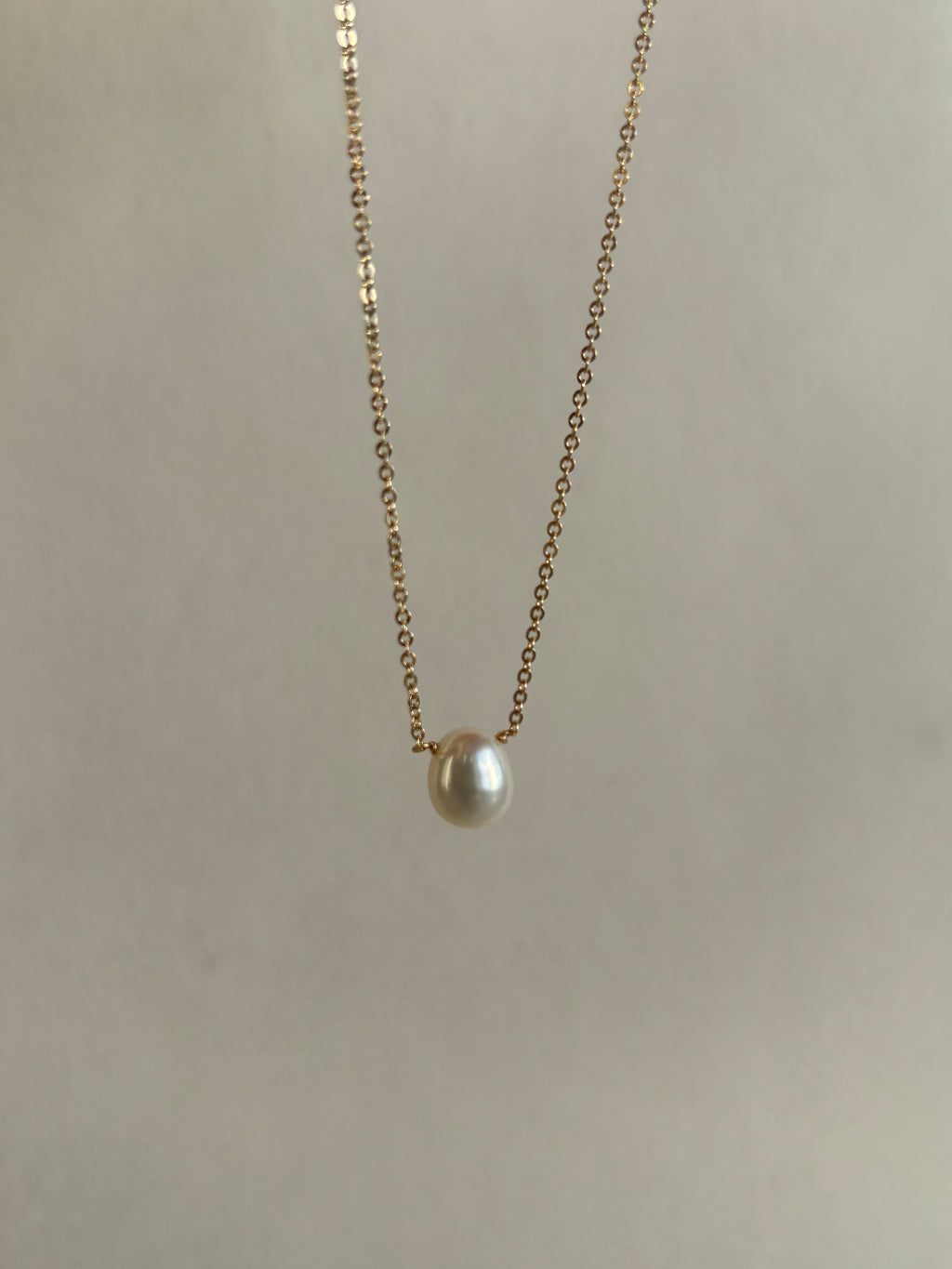 Thalken yellow gold-filled necklace with a luminous pearl drop suspended in the air