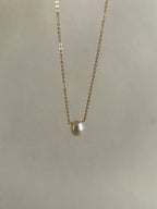 Thalken yellow gold-filled necklace with a luminous pearl drop suspended in the air