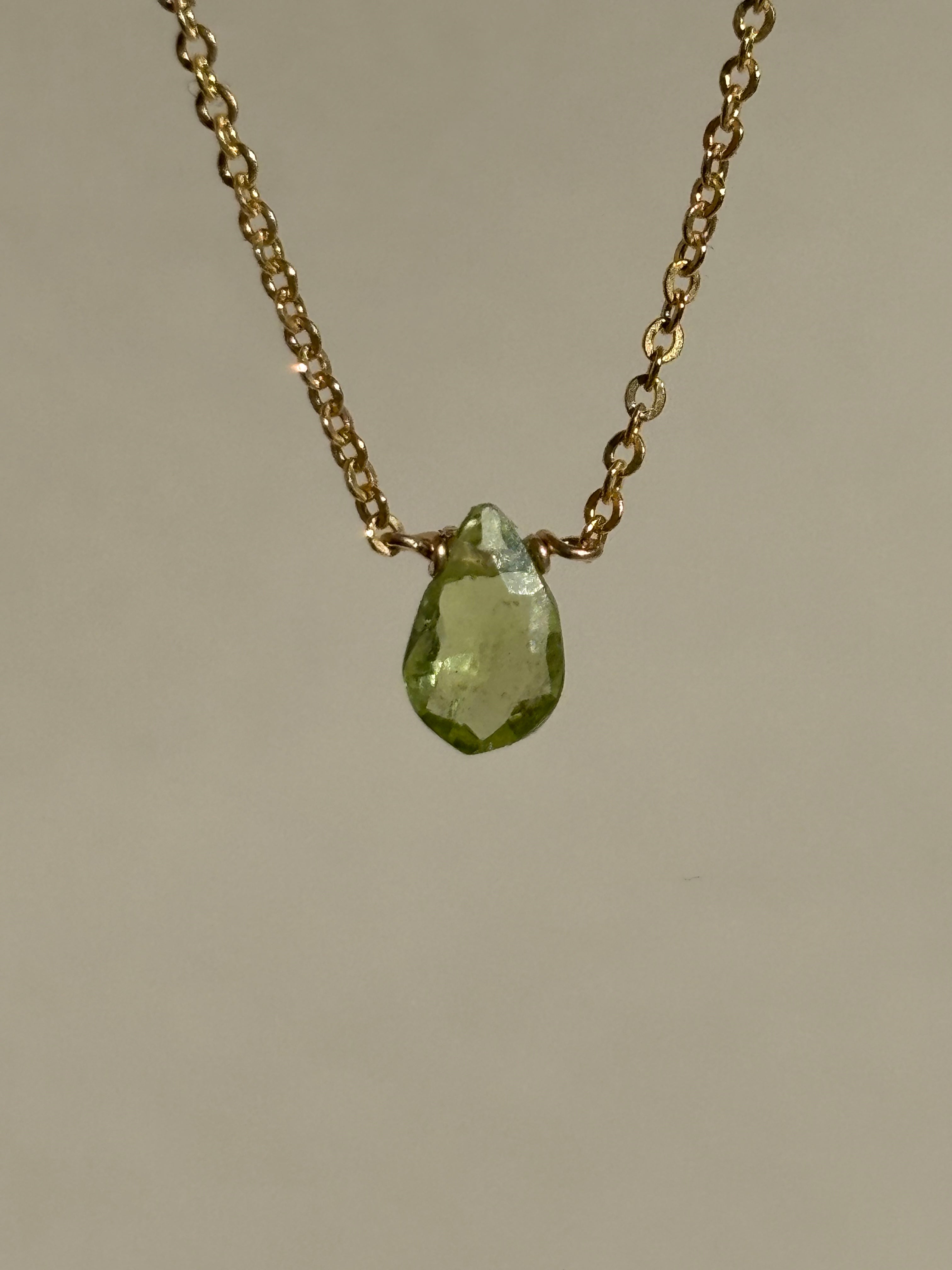 Peridot Drop Necklace against a neutral backdrop, angled for a closer view of the peridot pendant and chain details
