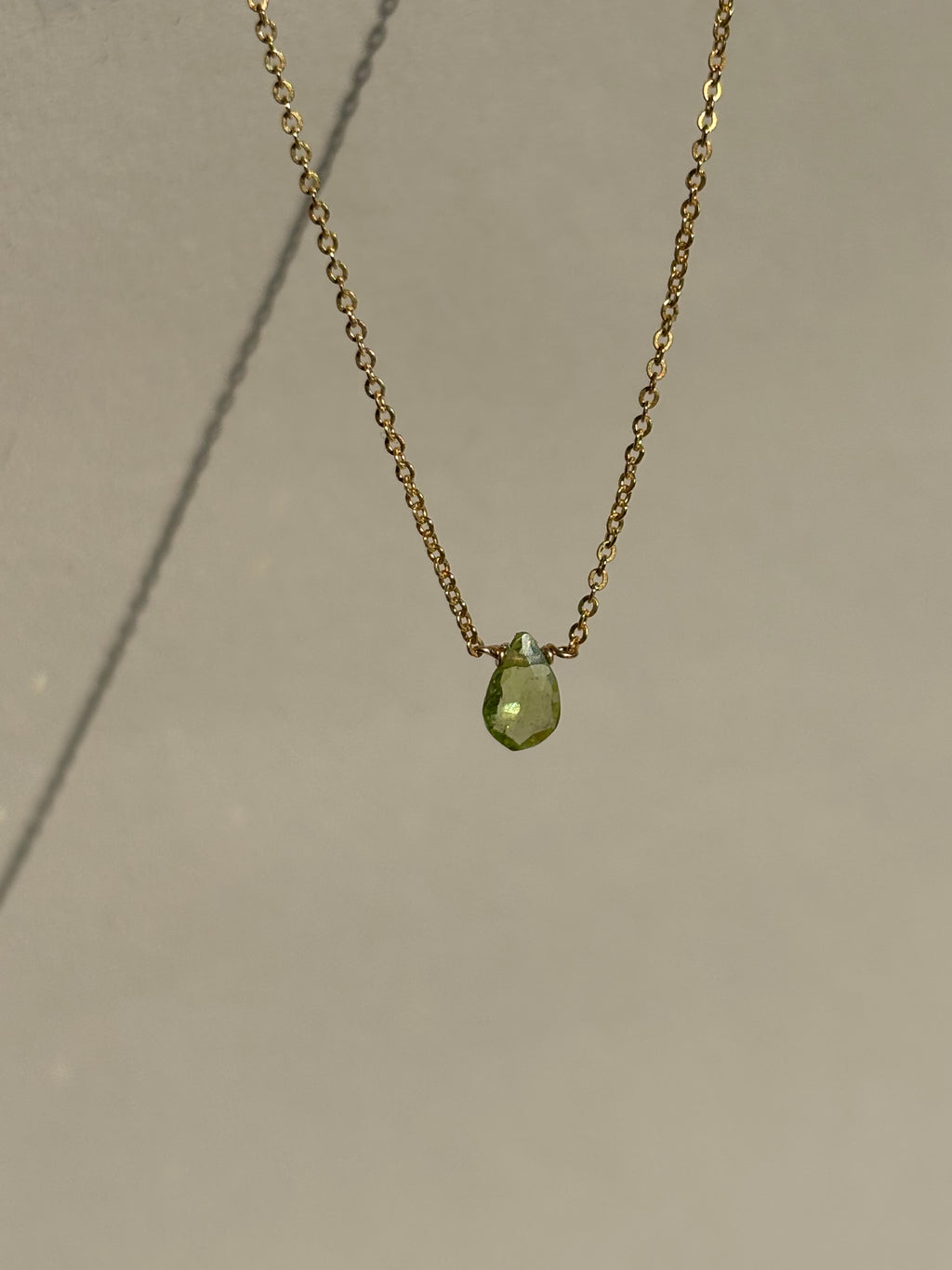 Peridot Drop Necklace suspended in air, showcasing the faceted peridot gemstone and delicate chain