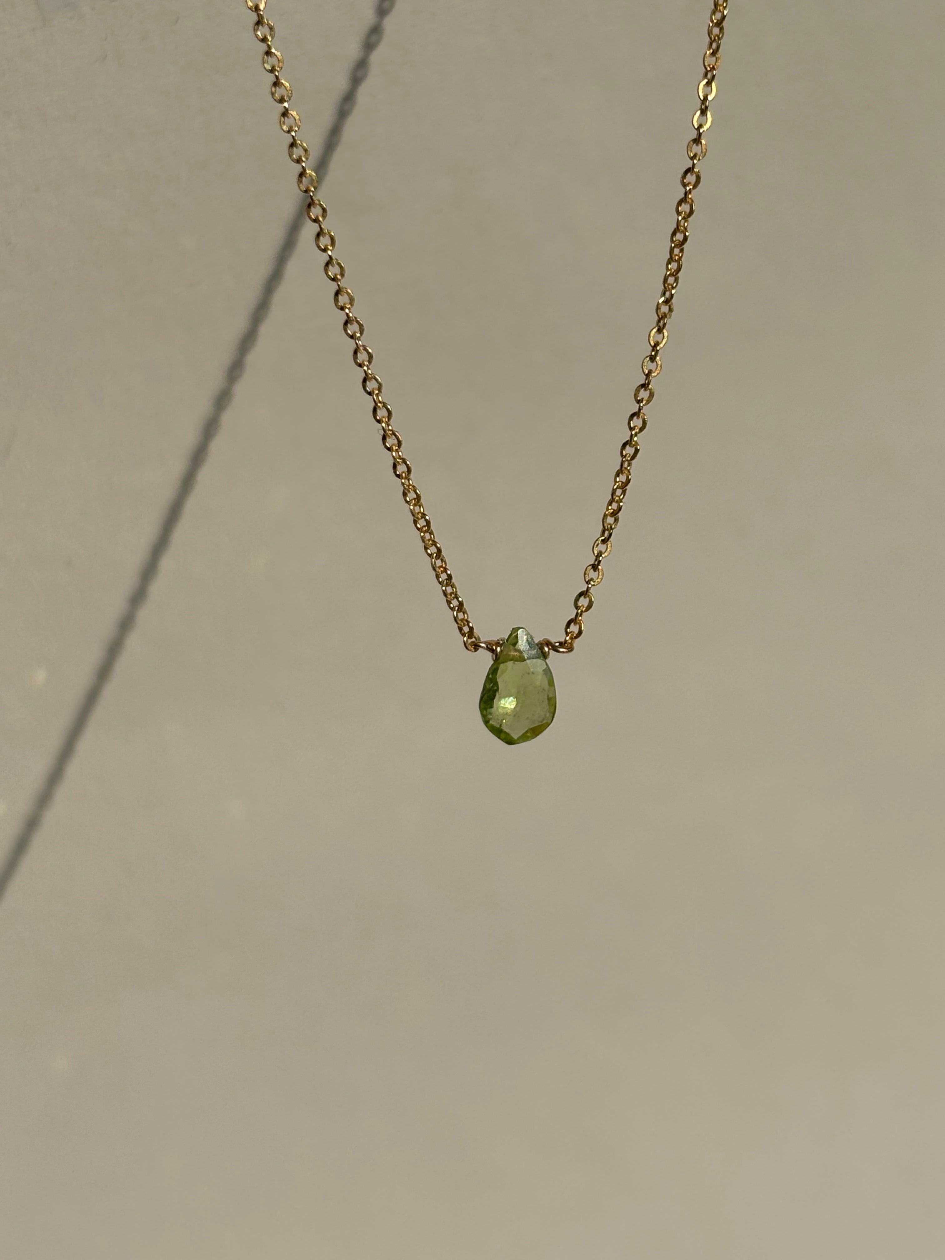 Peridot Drop Necklace suspended in air, showcasing the faceted peridot gemstone and delicate chain