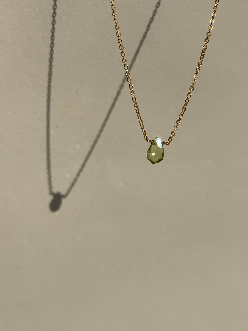 Peridot Drop Necklace suspended in air against a neutral backdrop, front view highlighting the green gemstone pendant