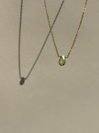 Peridot Drop Necklace suspended in air against a neutral backdrop, front view highlighting the green gemstone pendant