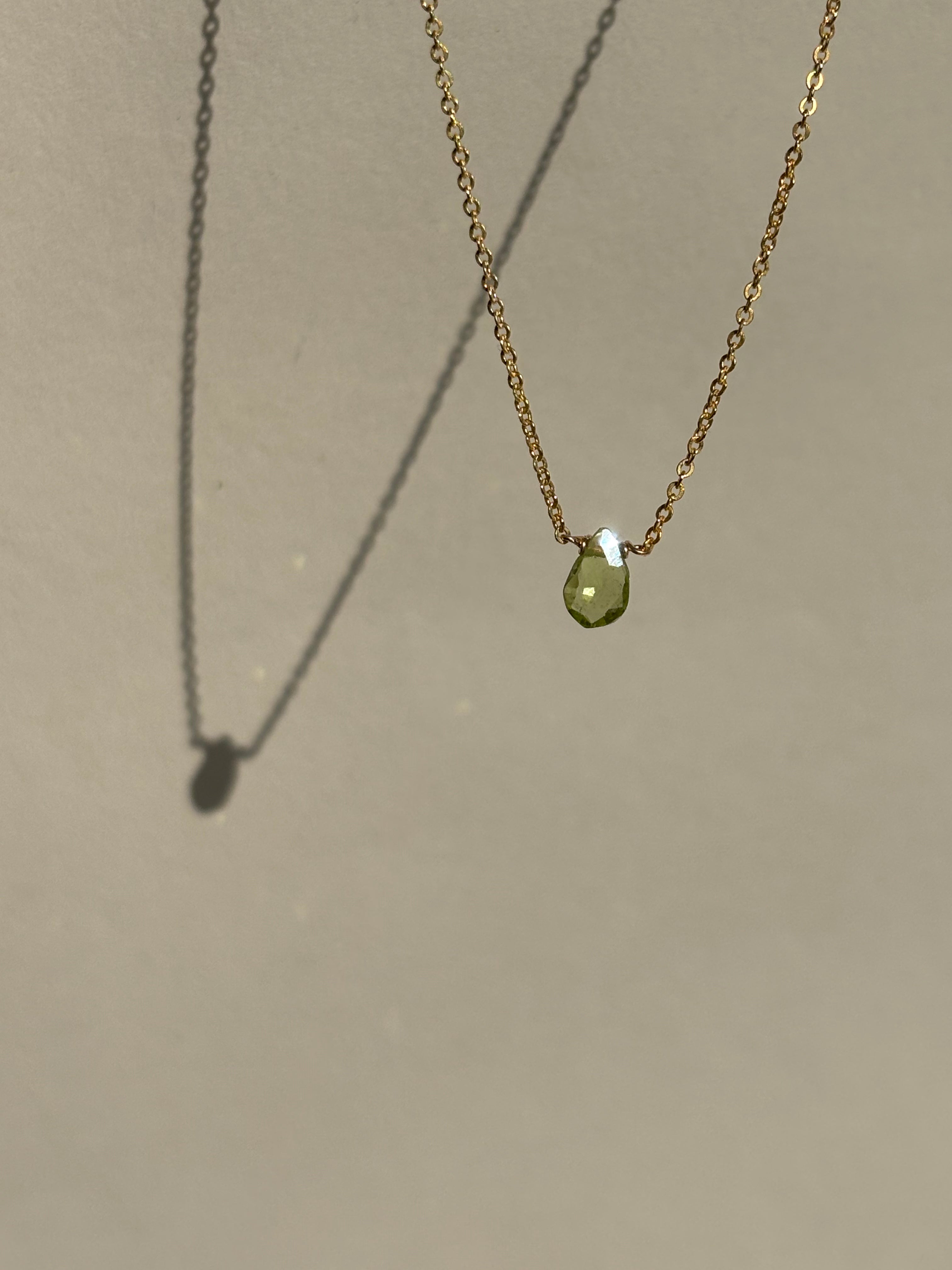 Peridot Drop Necklace suspended in air against a neutral backdrop, front view highlighting the green gemstone pendant