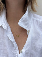 Model wearing dainty peridot drop necklace in white linen shirt