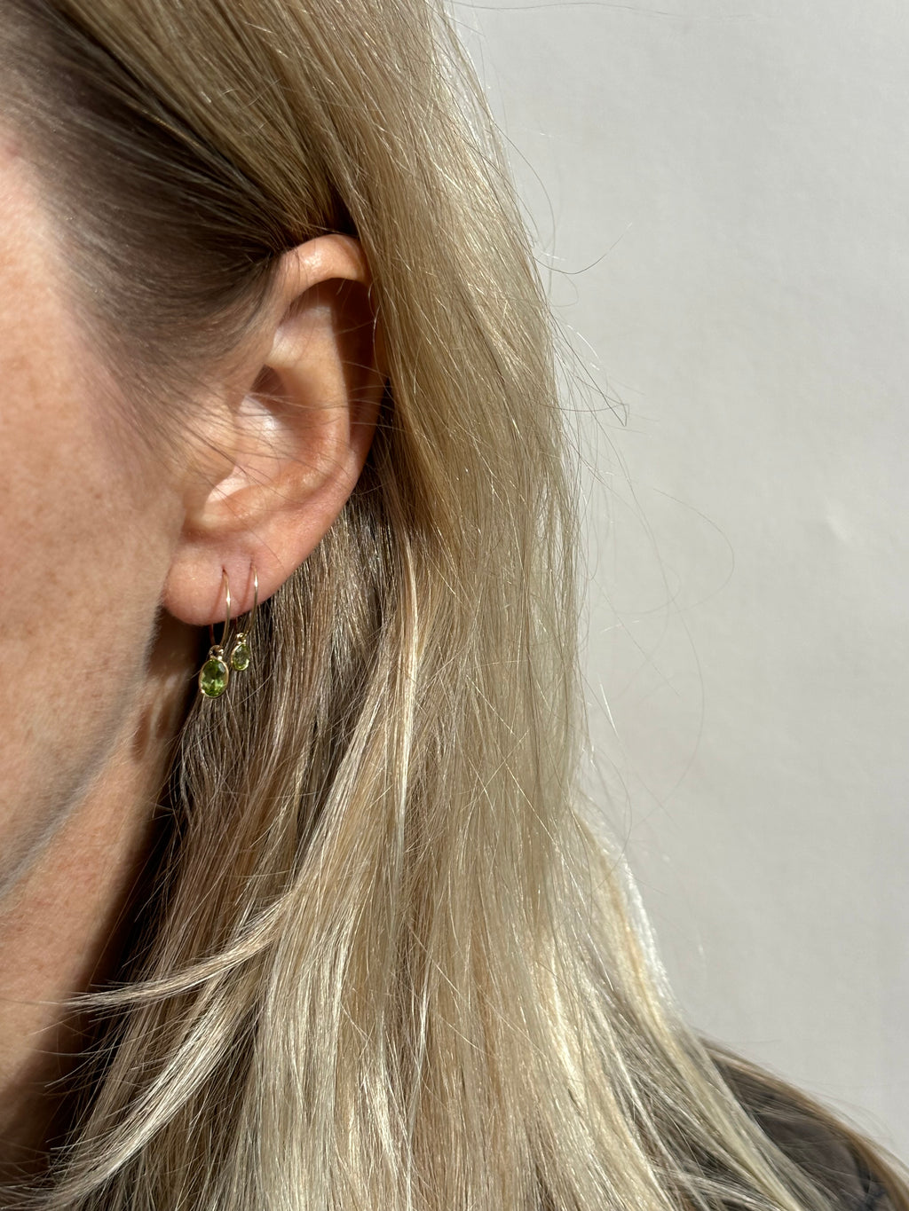 Close up on model wearing a 12mm hoop with the medium oval drop in her first ear piercing, and a 10mm hoop with the small oval drop in her second ear piercing