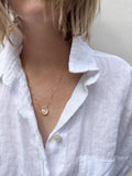 Woman wearing a flat freshwater pink pearl resembling a petal fixed on a dainty yellow gold-filled chain