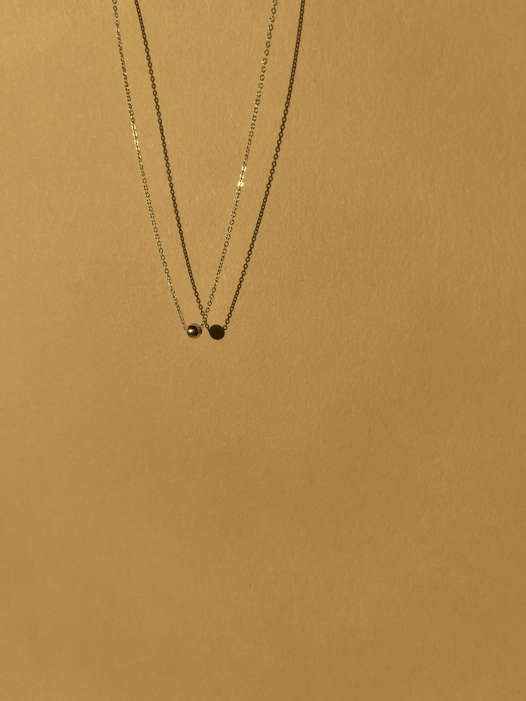 Sterling silver Petite Ball Choker necklace floating against a sunlit neutral backdrop, emphasizing its delicate 4mm accent bead and dainty chain