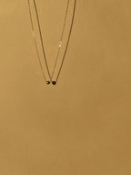 Sterling silver Petite Ball Choker necklace floating against a sunlit neutral backdrop, emphasizing its delicate 4mm accent bead and dainty chain