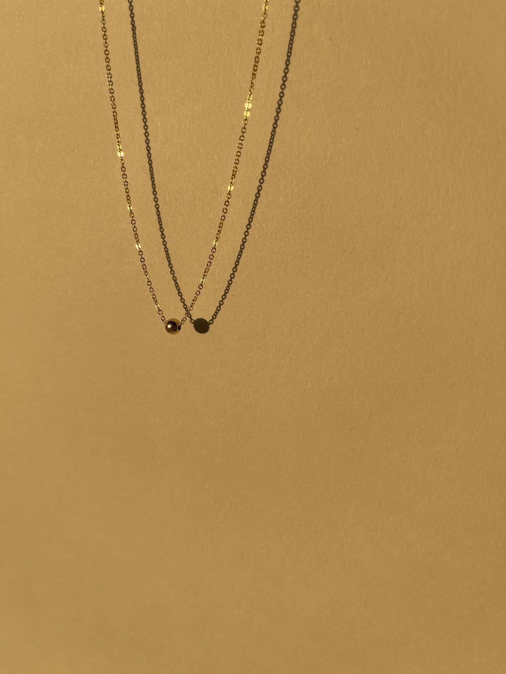 Yellow gold-filled Petite Ball Choker necklace suspended in air against a softly sunlit neutral backdrop, minimalist and glowing