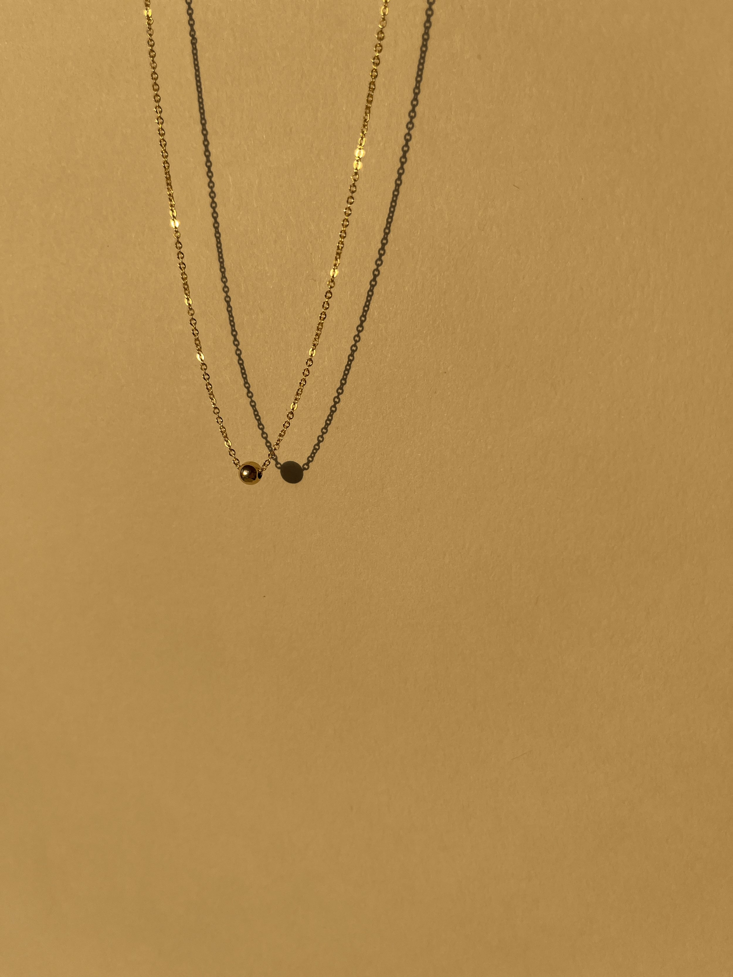 Yellow gold-filled Petite Ball Choker necklace suspended in air against a softly sunlit neutral backdrop, minimalist and glowing