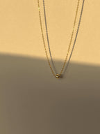 Shot of the yellow gold-filled Petite Ball Choker floating against a warm, softly glowing neutral backdrop, showcasing its dainty design