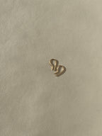 Distant shot of a pair of Petite R Staple Earrings in yellow gold-filled, showcasing its sleek, modern R-shaped design with a polished finish