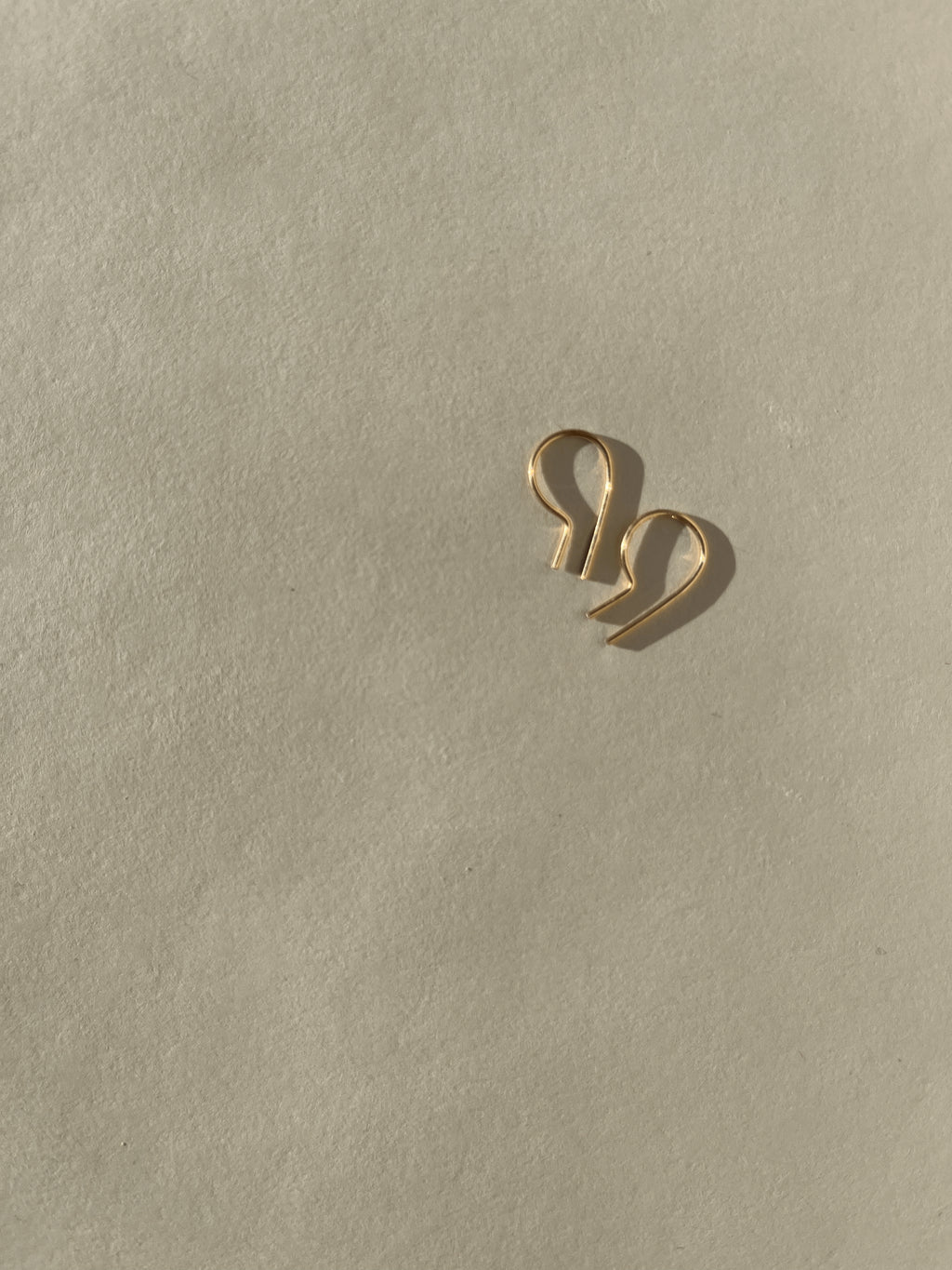 Close-up of a pair of Petite R Staple Earrings in yellow gold-filled, showcasing its sleek, modern R-shaped design with a polished finish