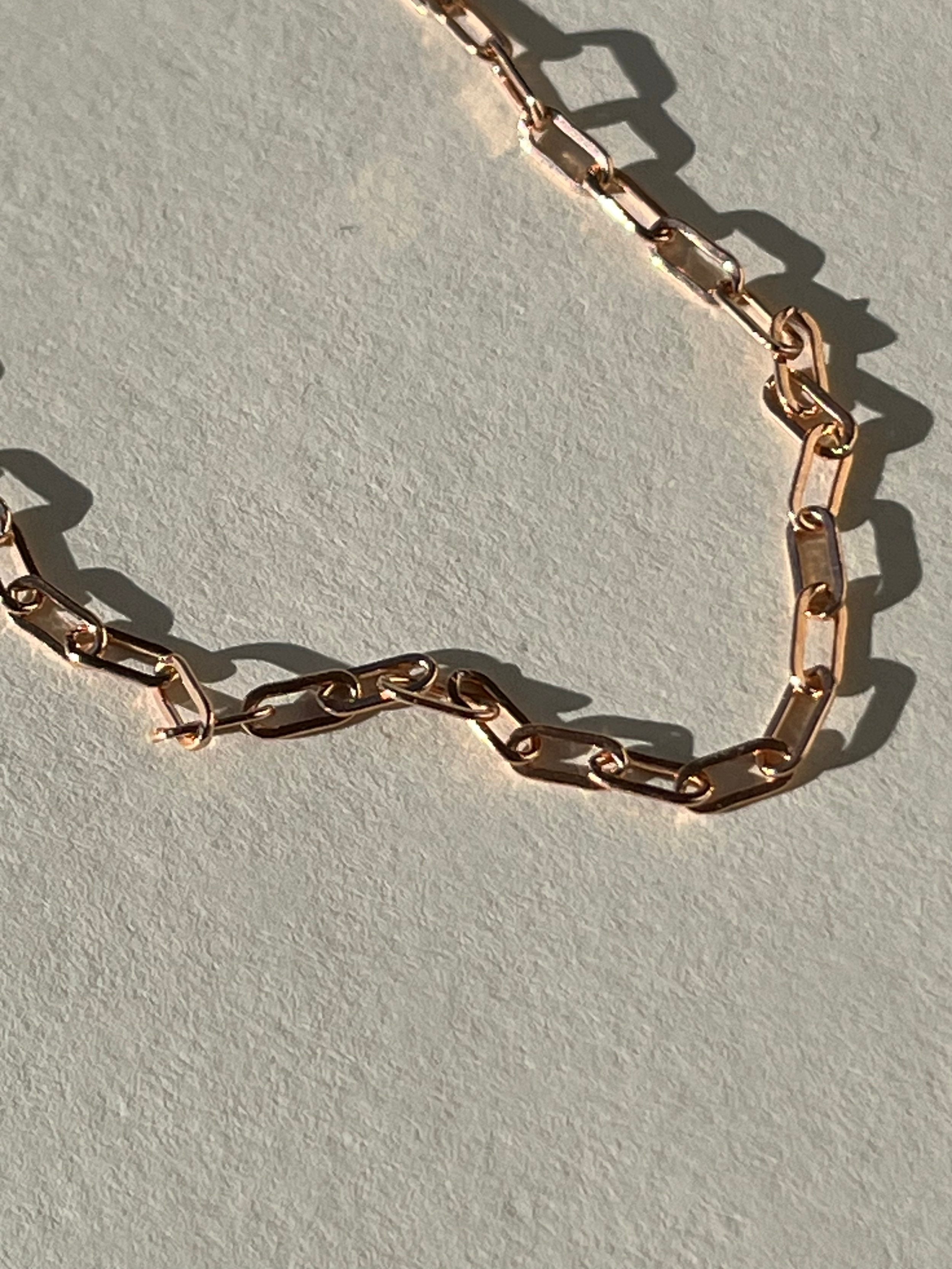 Close-up of the rose gold-filled small link paperclip necklace in warm lighting, highlighting the fine detail of the links