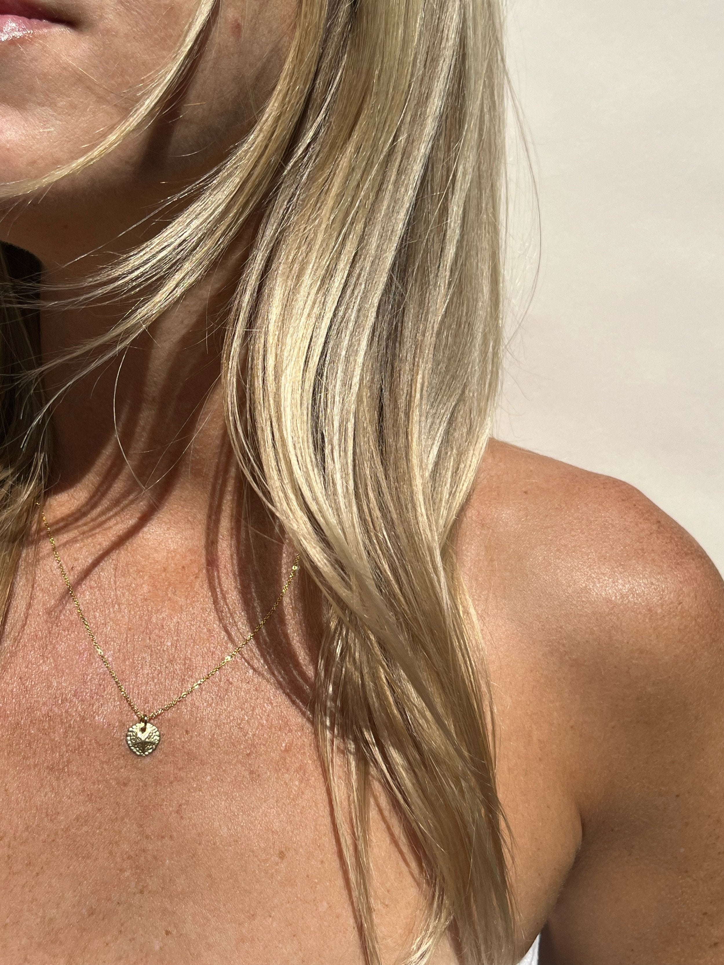 Model wearing the yellow gold-filled 10mm Sand Dollar Necklace with an 18” chain, delicate and coastal-inspired