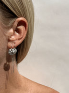 Model wearing sterling silver sand dollar threader earrings in both ears, 12mm in the first piercing and 10mm in the second